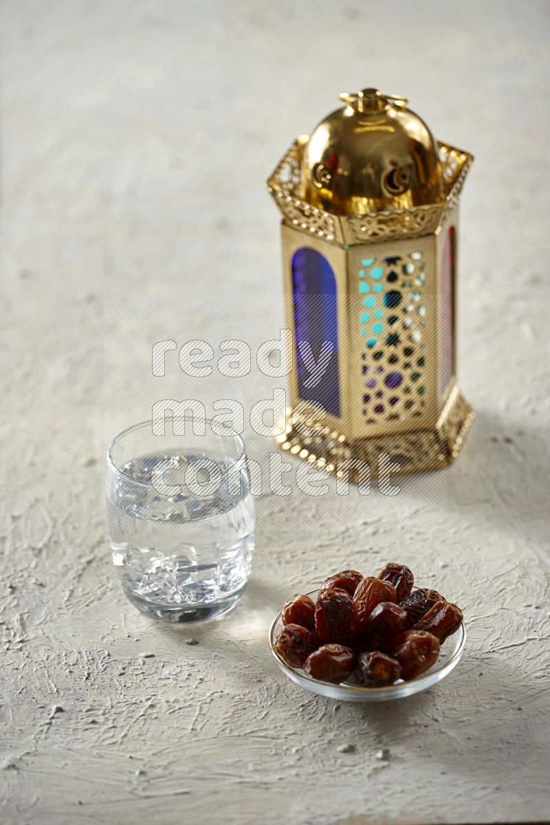 A golden lantern with different drinks, dates, nuts, prayer beads and quran on textured white background