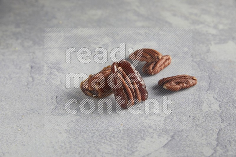 TWO pecan stuffed dates on alight grey background