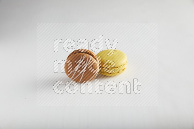 45º Shot of of two assorted Brown Irish Cream, and Yellow Lemon macarons on white background