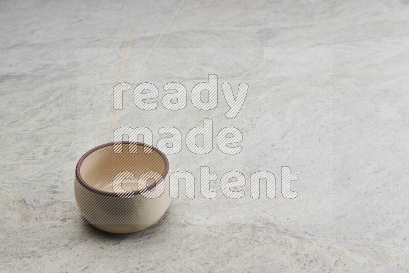 A beige pottery oven bowl on grey marble background