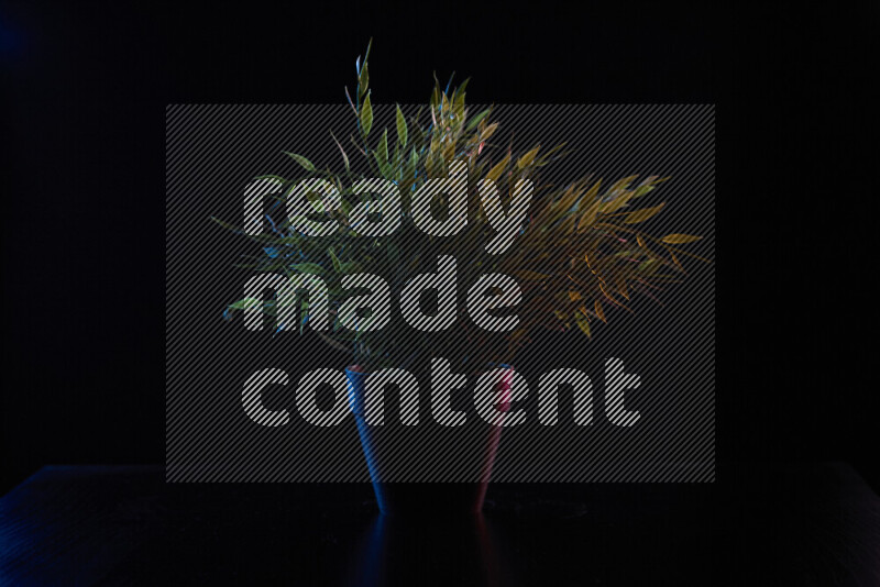 Plastic potted plant with colored rim light against black background