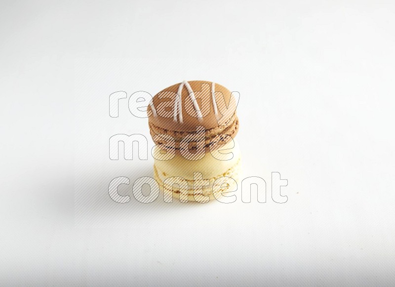 45º Shot of of two assorted Brown Irish Cream, and Yellow Vanilla macarons on white background