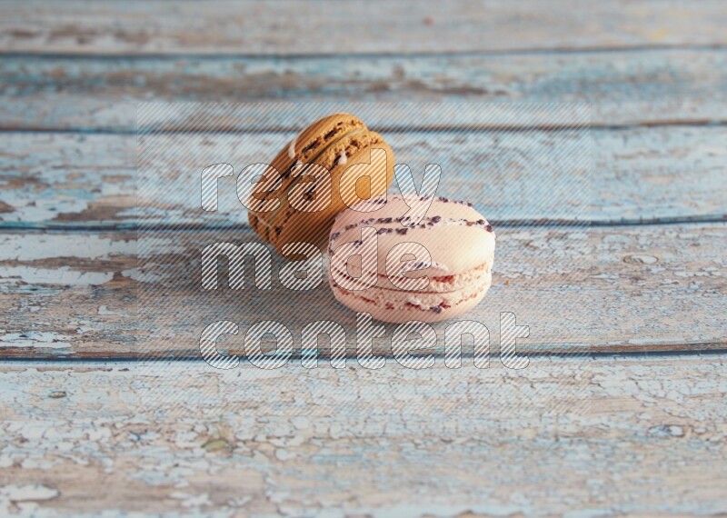 45º Shot of of two assorted Brown Irish Cream, and pink orange blossom  macarons on light blue background
