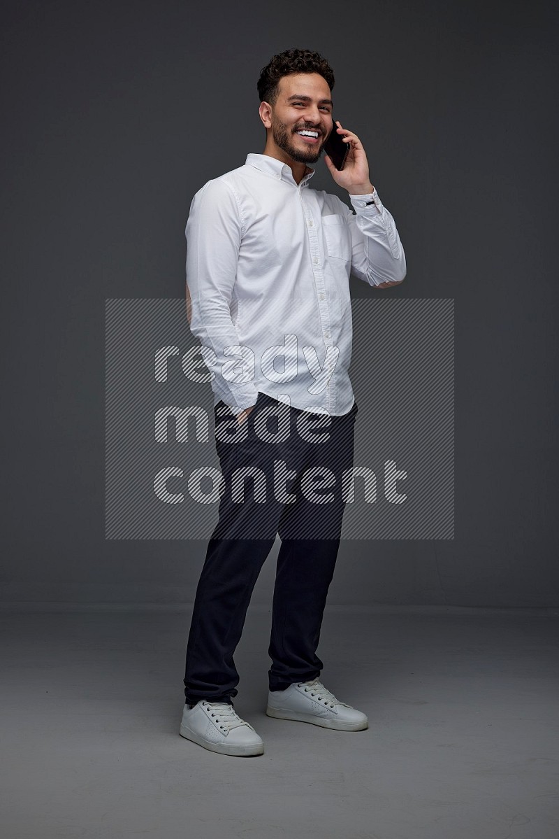 A man wearing smart casual talking in the phone eye level on a gray background