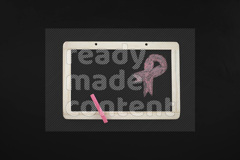 A drawing of pink ribbon on blackboard on black background