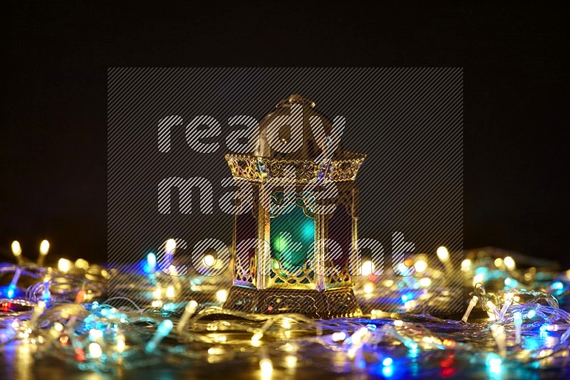 A golden lantern with fairy light in a dark setup