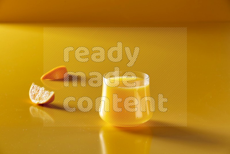 glass of orange juice on yellow background