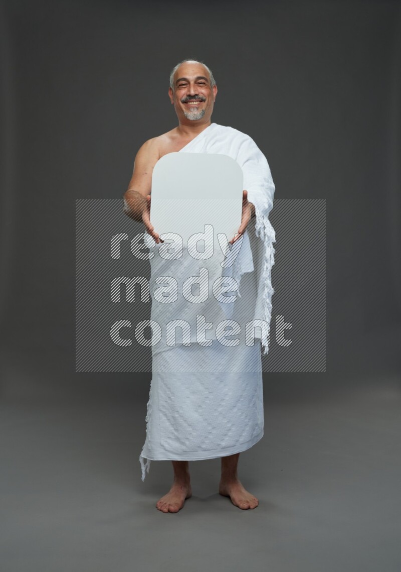A man wearing Ehram Standing holding social media sign on gray background