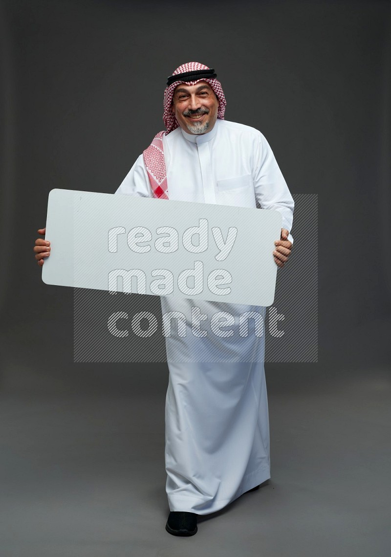 Saudi man with shomag Standing holding social media sing on gray background