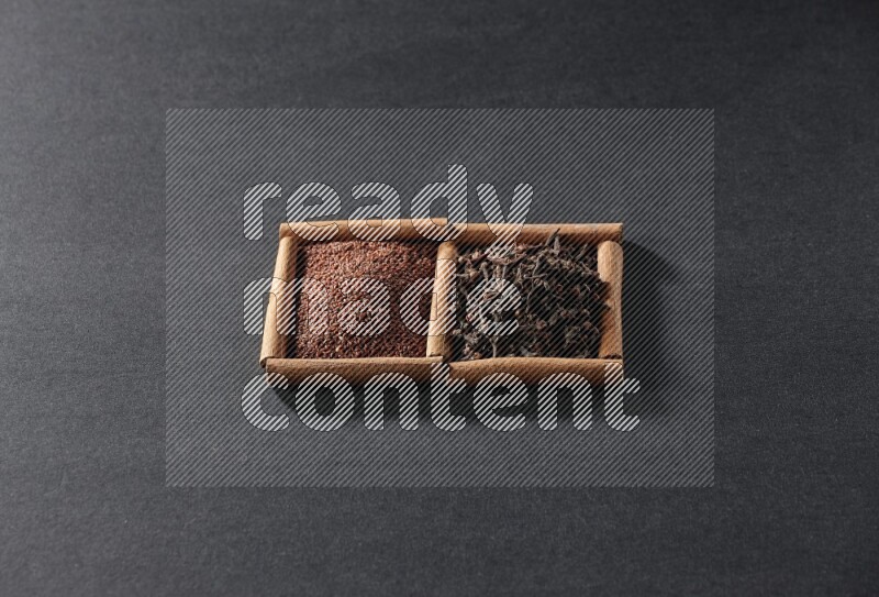 مربعان من أعواد القرفة ممتلئان بحب الرشاد والقرنفل علي خلفية سوداء