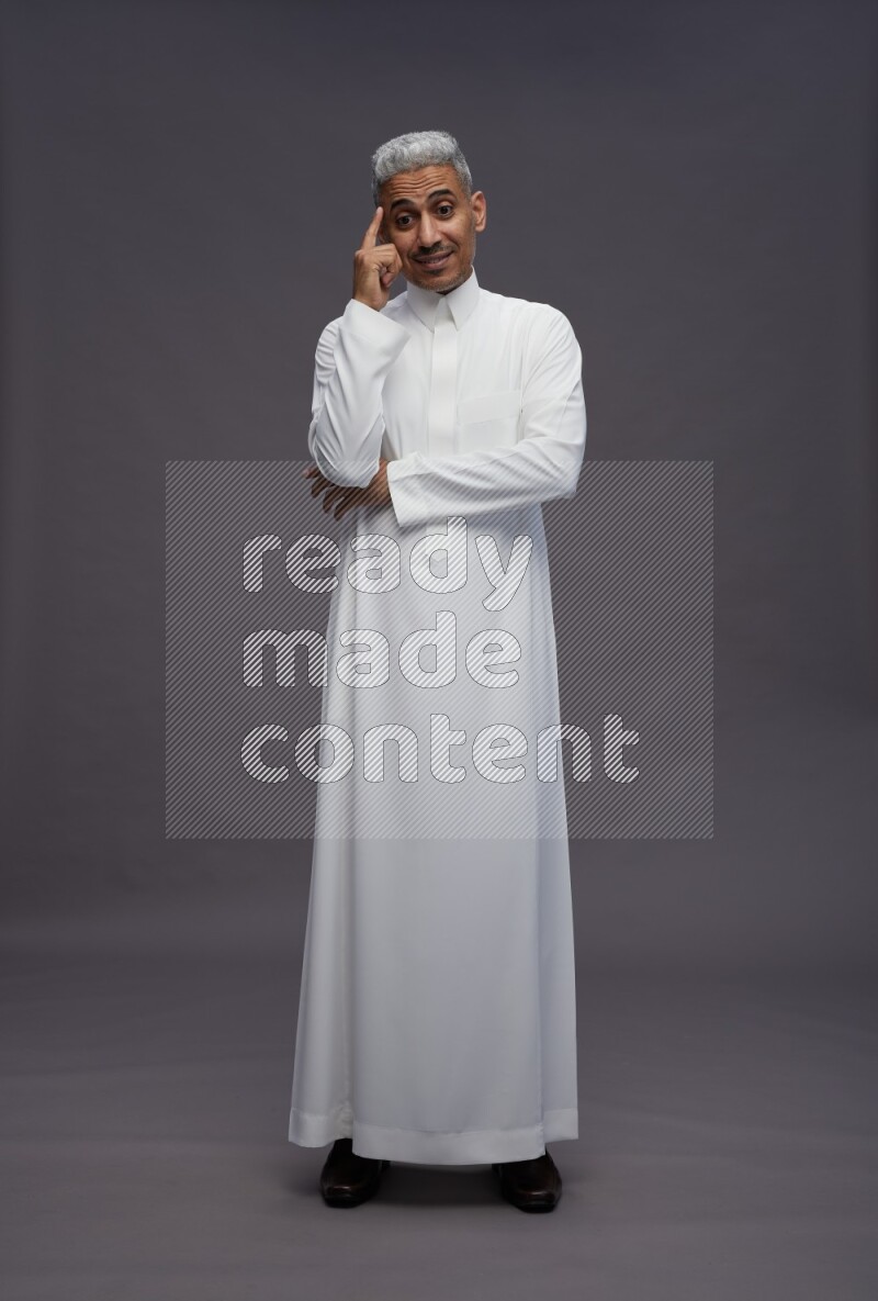 Saudi man wearing thob standing interacting with the camera on gray background