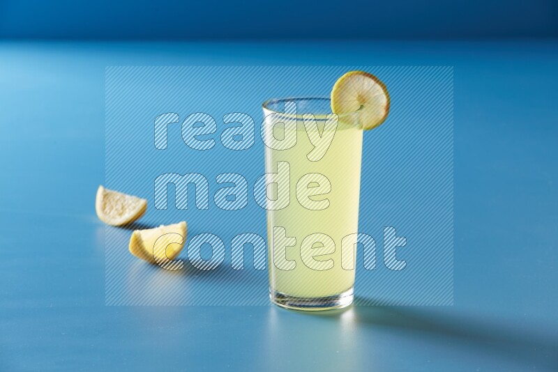 glass of lemon juice with lemon slice  on blue background