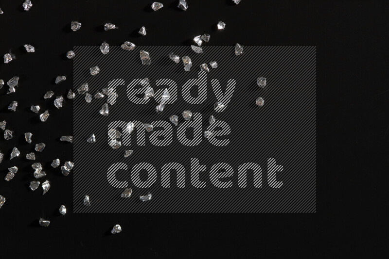 Silver shimmering fragments of glass scattered on a black background