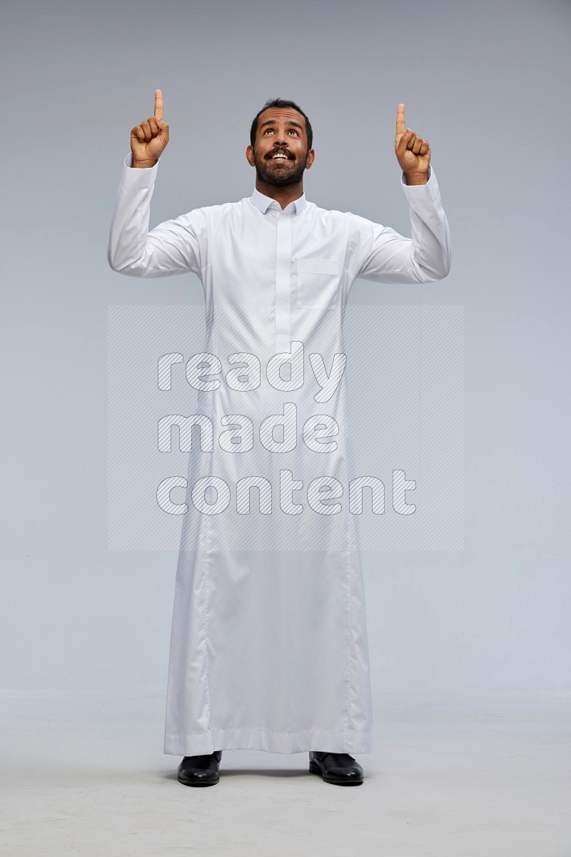 Saudi man Wearing Thob standing interacting with the camera on Gray background