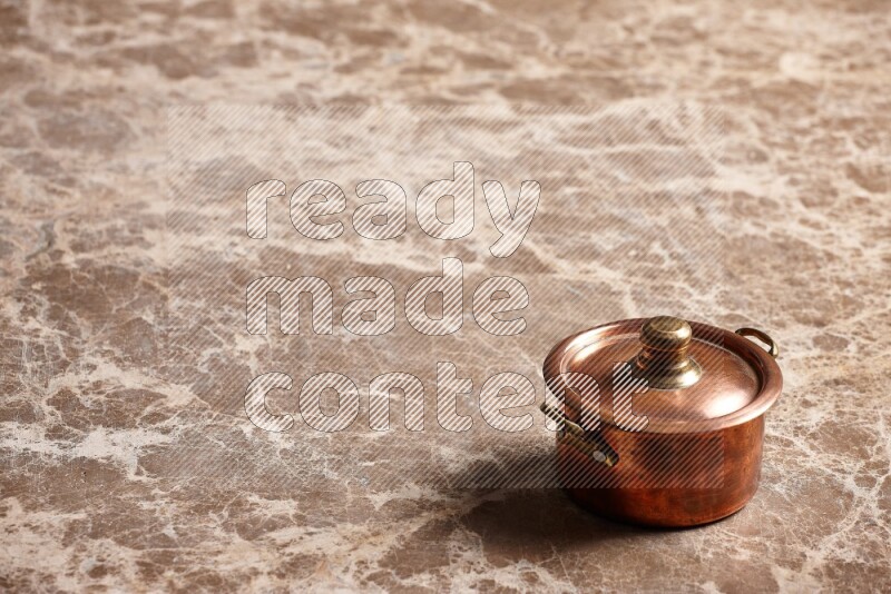 A small copper pot on beige marble background
