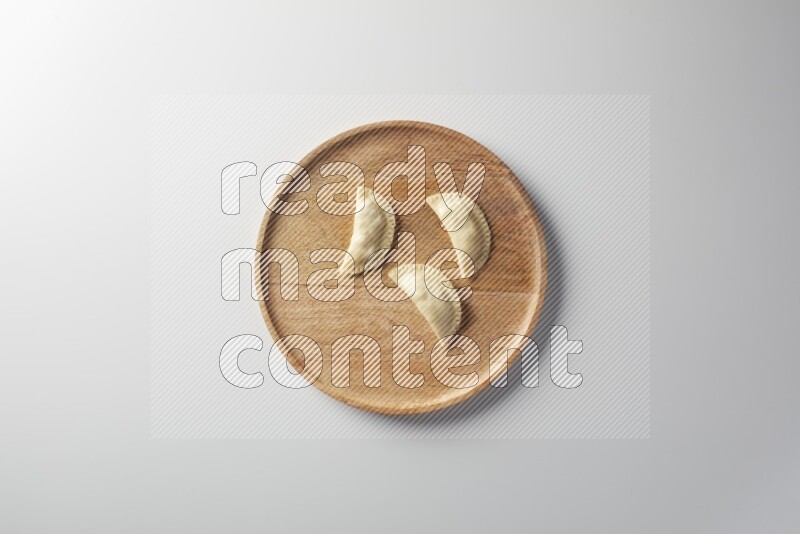 Three Sambosas on a wooden round plate on a white background