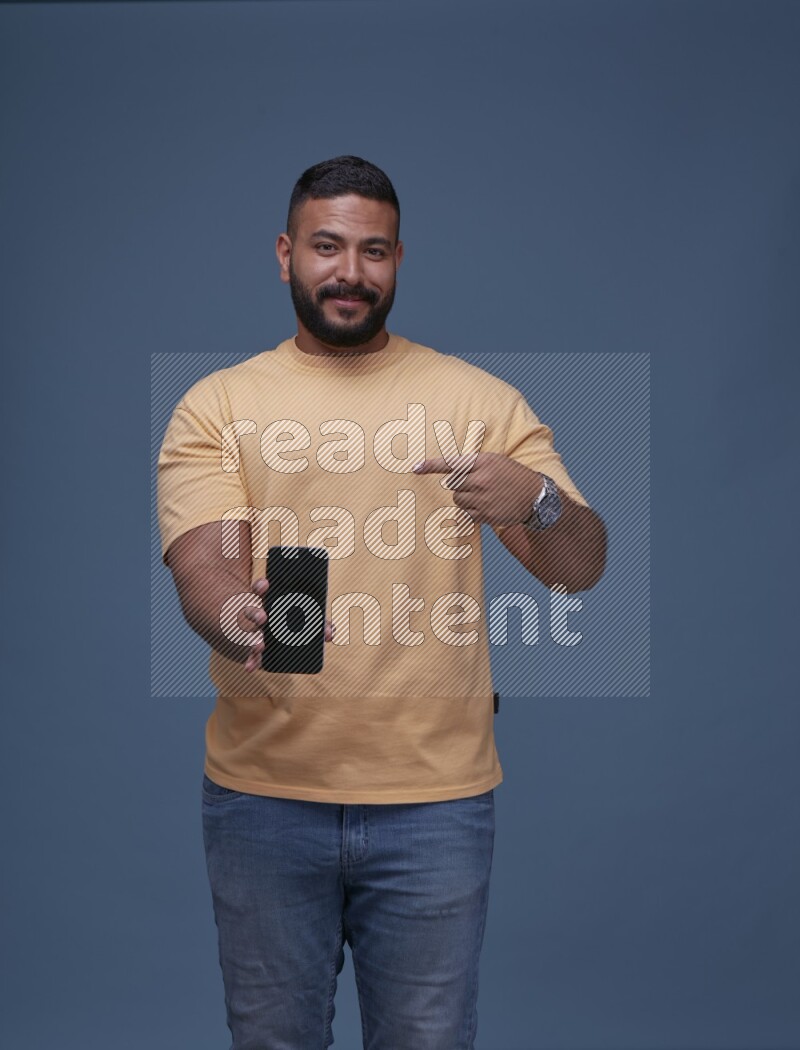 A man Showing His Smart Phone on Blue Background wearing Orange T-shirt