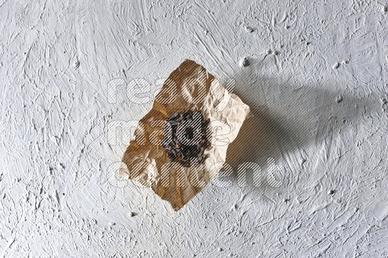 Cloves on crumpled piece of paper on a textured white flooring