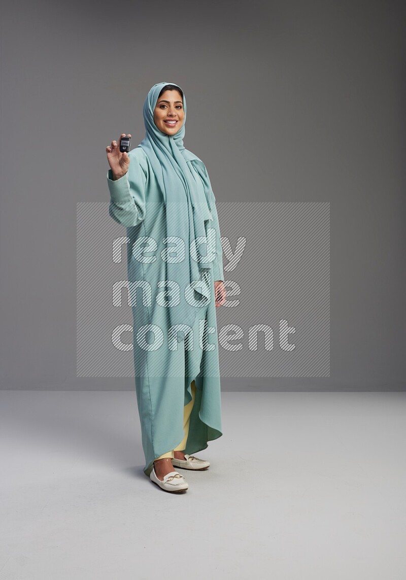 Saudi Woman wearing Abaya standing holding car key on Gray background