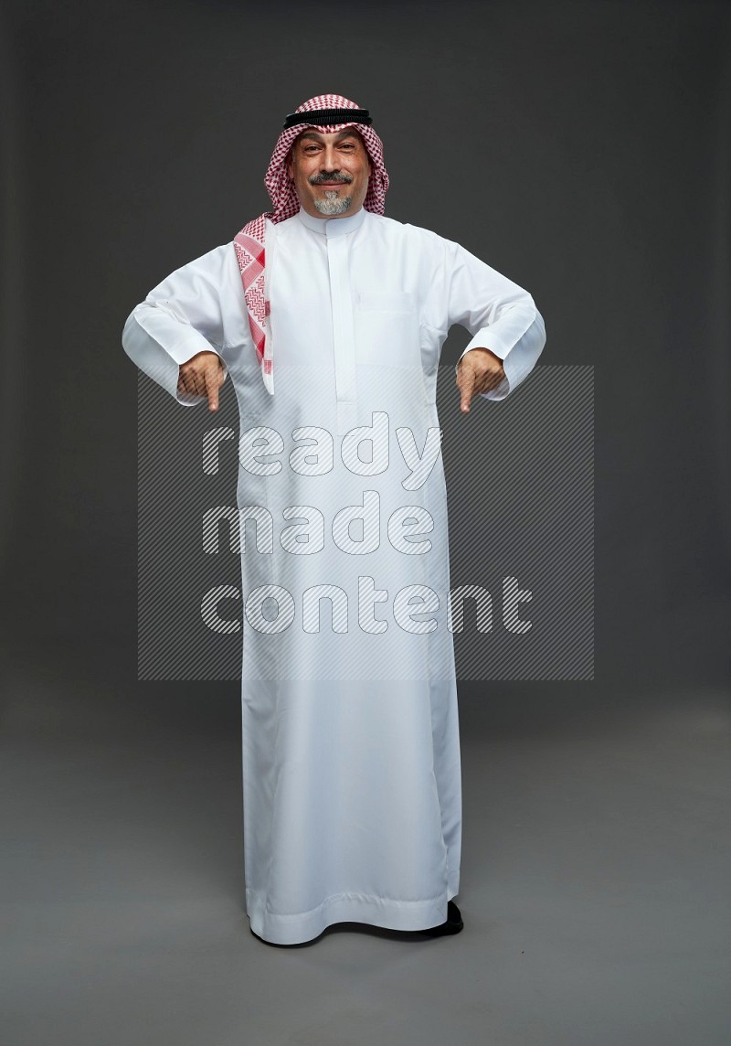 Saudi man with shomag Standing Interacting with the camera on gray background