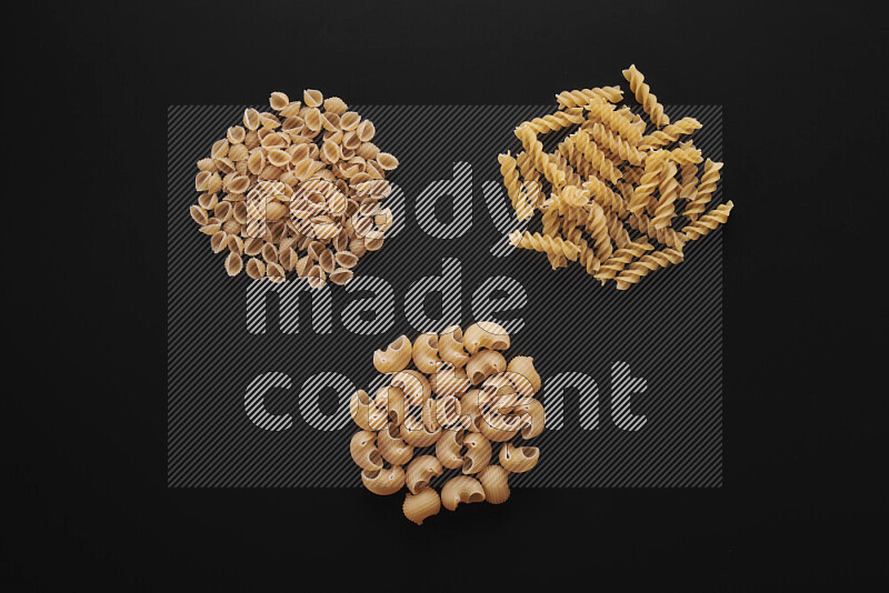 Different pasta types in bunches on black background