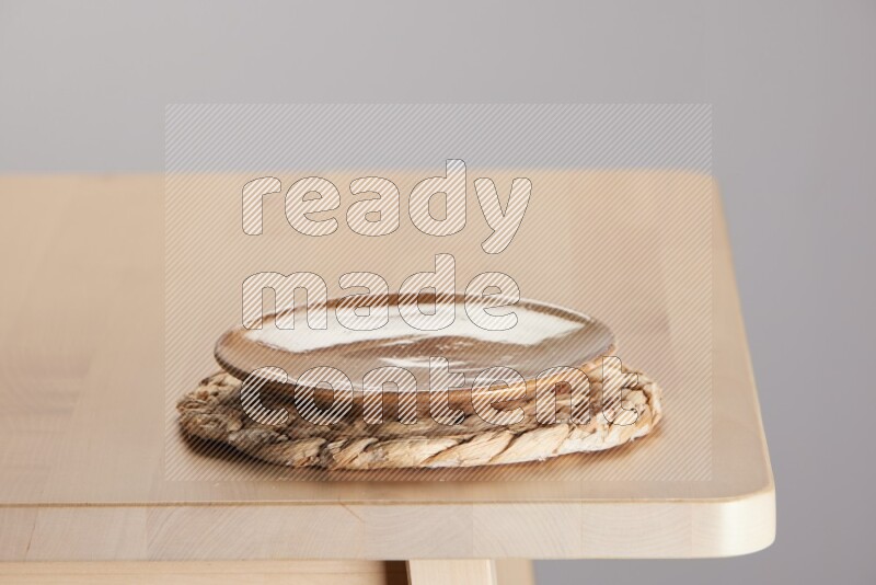 multi-colored pottery Plate placed on a small light colored straw placemat on the edge of wooden table