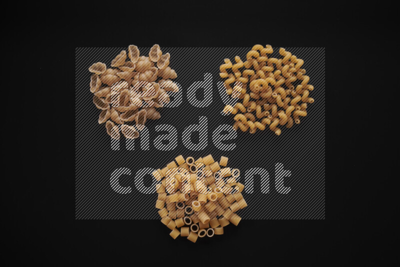 Different pasta types in bunches on black background