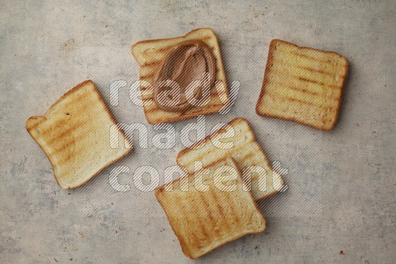 Creamy peanut butter on a toasted white toast and toasted white toast slices on a light blue textured background