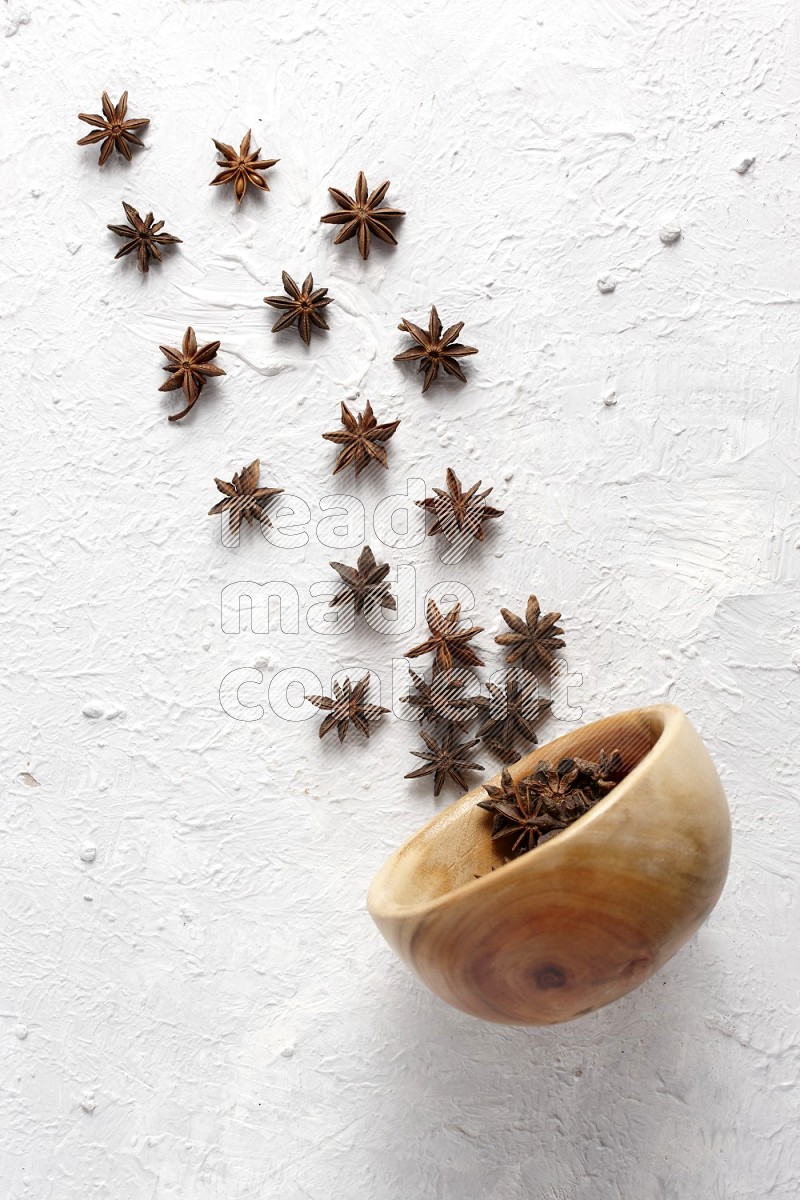 Star anise lined out of wooden plate across the frame on white background