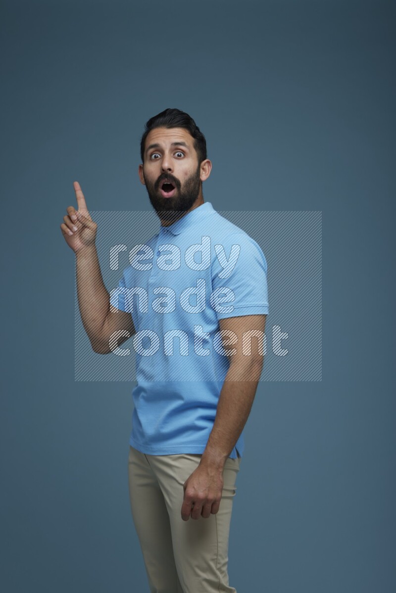 A man pointing  in a blue background wearing a Blue shirt