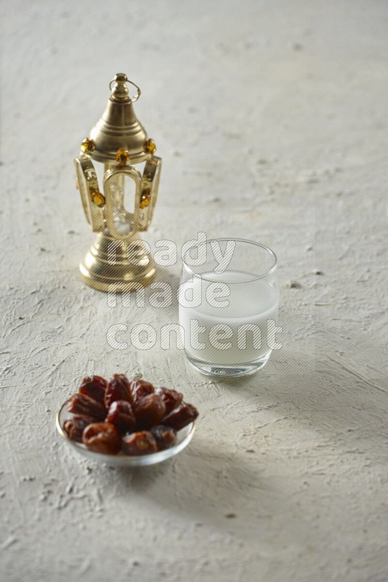 A golden lantern with different drinks, dates, nuts, prayer beads and quran on textured white background