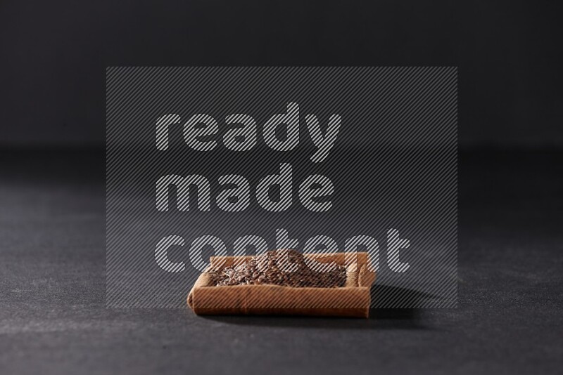 أربعة من أعواد القرفة مكونة شكل مربع بداخلها بذور الكتان علي خلفية سوداء