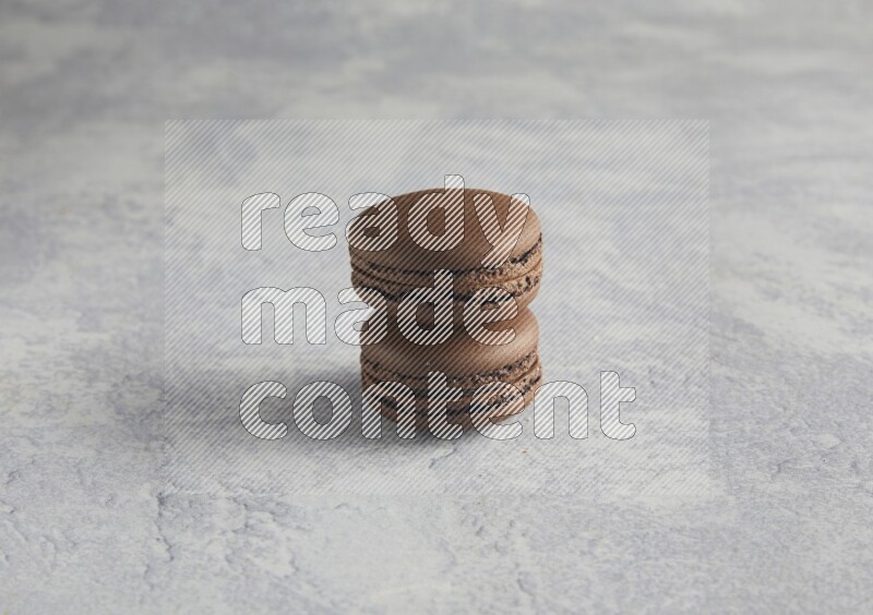 45º Shot of two Brown Dark Chocolate macarons  on white  marble background
