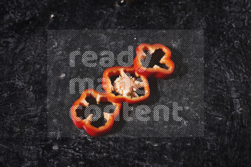 Red bell pepper slices on black background