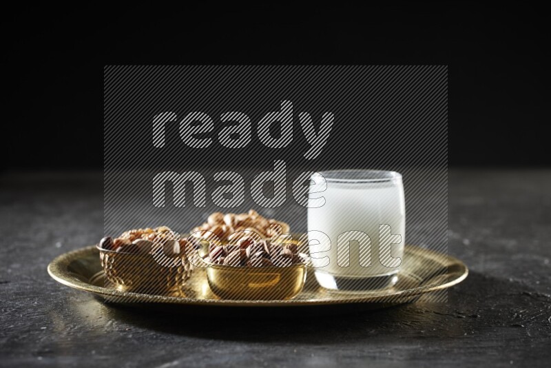 Nuts in metal bowls with sobya on a tray in dark setup