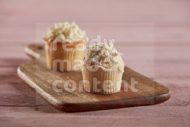 Vanilla mini cupcake topped with coconut on a wooden board