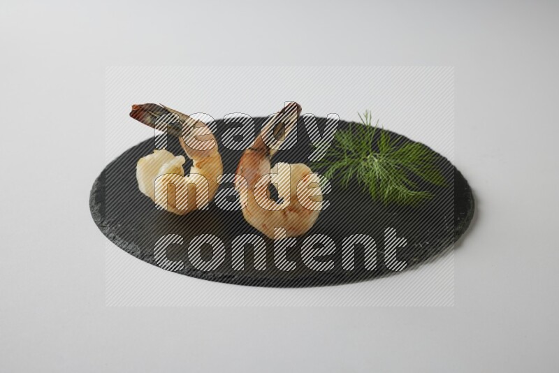 two grilled shrimp  on a black slate direct  on a white back ground