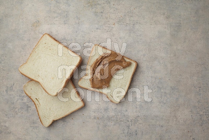 Creamy peanut butter on white toast and white toast slices on a light blue textured background