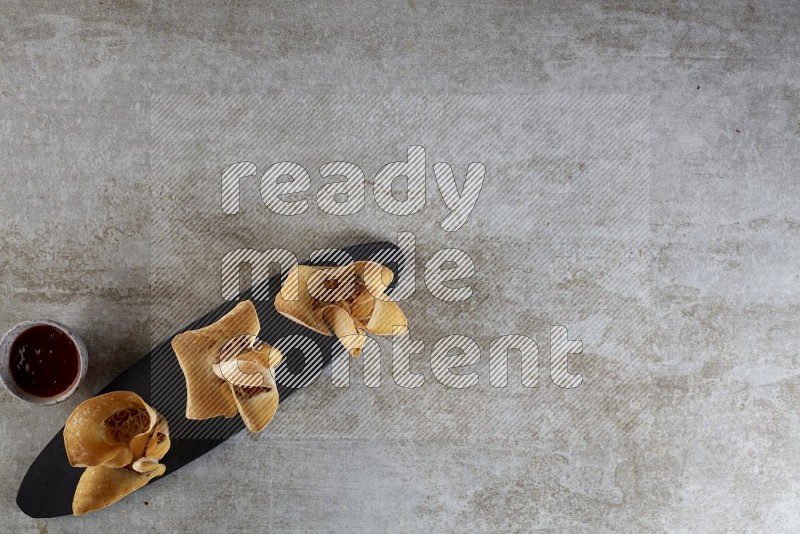 wonton cups with soy sauce ramkin on oval slate on grey textured counter top