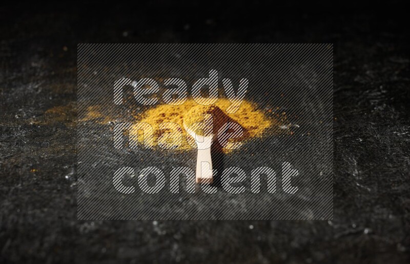 ملعقة خشبية ممتلئة ببودرة الكركم على خلفية سوداء