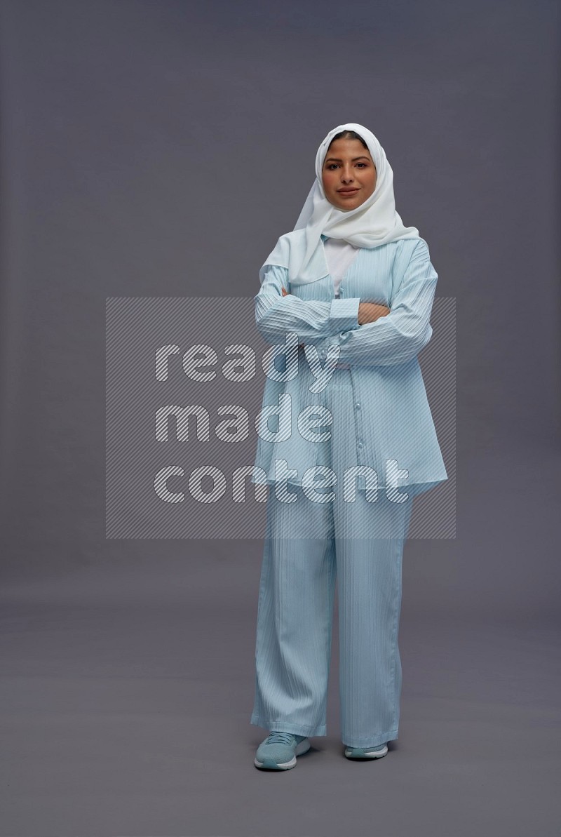 Saudi woman wearing hijab clothes standing with crossed arms on gray background