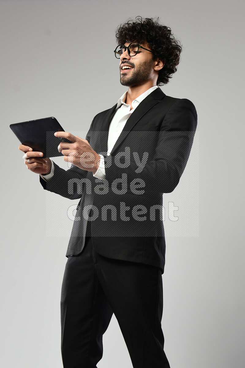 A man wearing formal standing and gaming on a tablet on white background