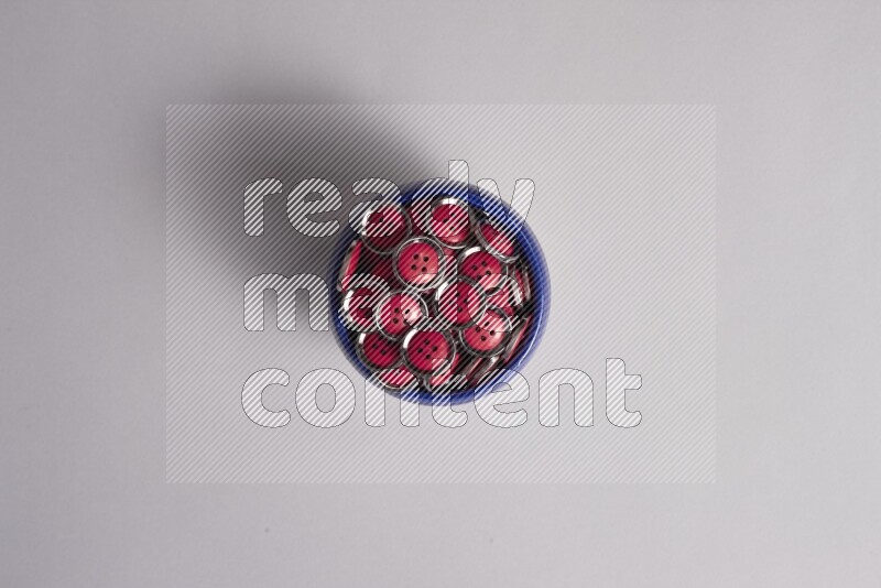 A multicolored pottery bowl full colored buttons on grey background