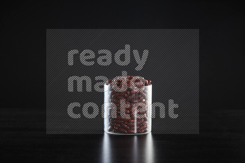 Red kidney beans in a glass jar on black background