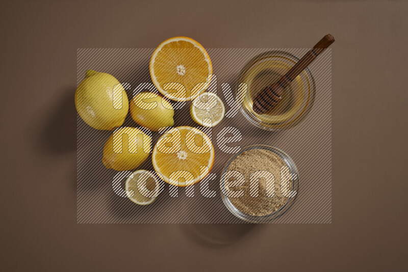 Two bowls full of honey and ground ginger with some of citrus fruits such as lemon and orange on a beige background