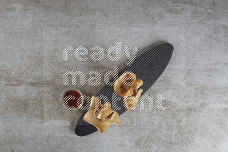 wonton cups with soy sauce ramkin on oval slate on grey textured counter top