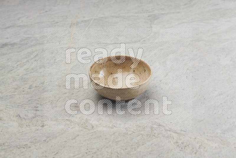 A small beige pottery bowl on grey marble background