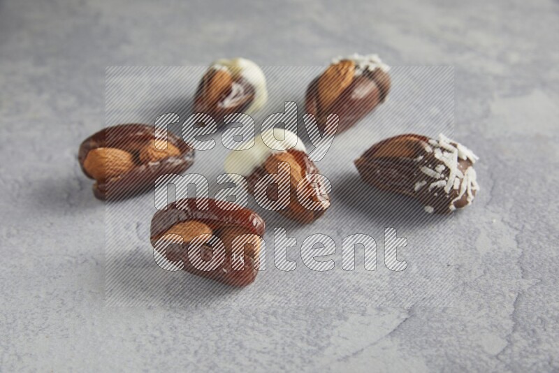 Group of Almonds stuffed dates plain and covered with chocolate on a light grey background