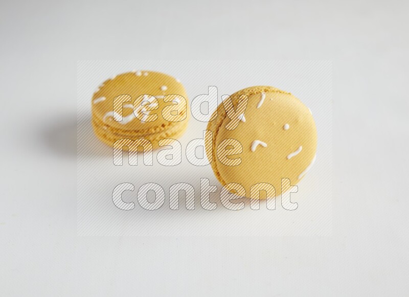 45º Shot of two Yellow Piña Colada macarons on white background