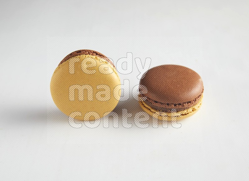 45º Shot of two Yellow and Brown Chai Latte macarons on white background